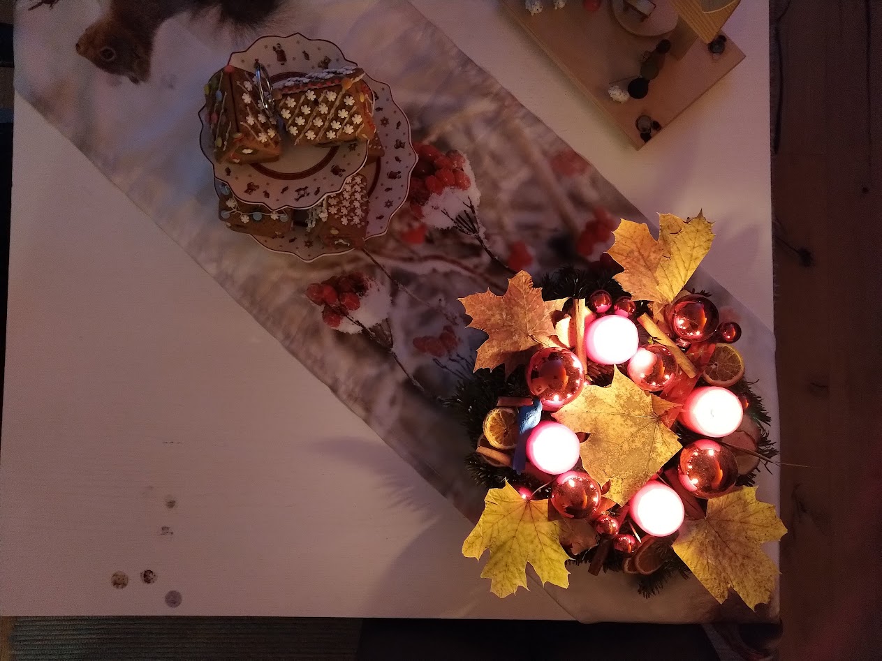 Combination of Christmas decorations with pyramid, table cloth, ginger bread houses and an advent ring.